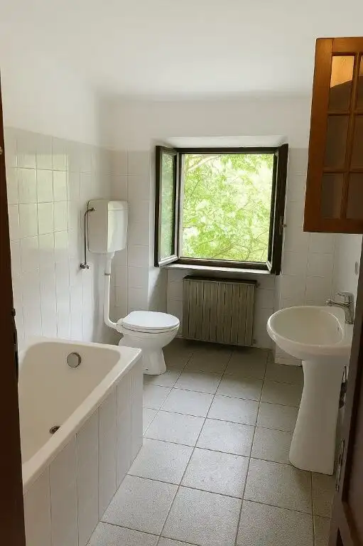 Bright bathroom with window and classic fixtures in Mezzana Mortigliengo Piedmont.