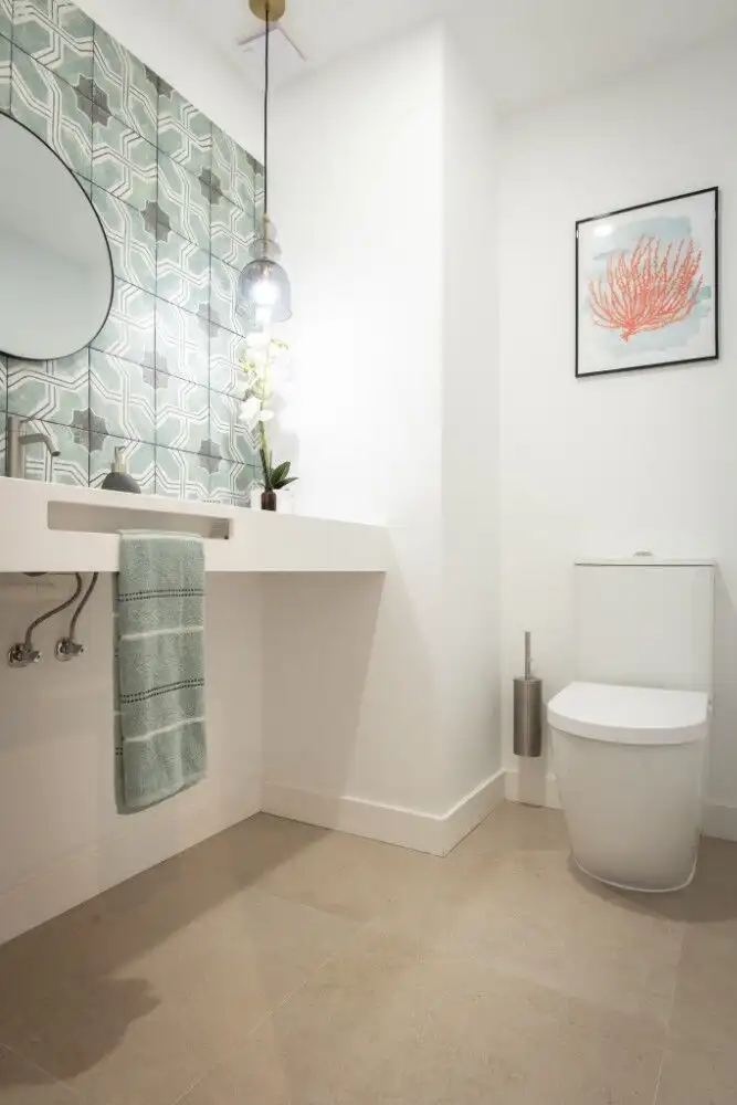 Bright, contemporary bathroom featuring a sleek toilet, decorative wall art, and elegant lighting fi.