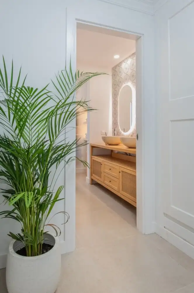 Bright bathroom featuring a wooden vanity, stylish vessel sink, and an elegant oval mirror.