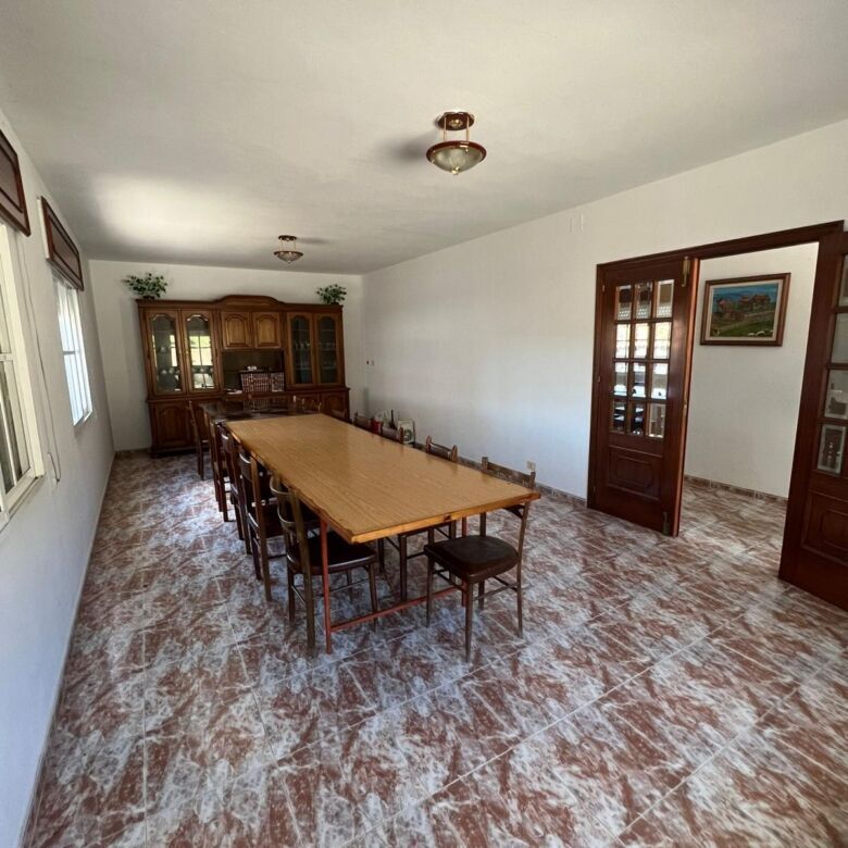 Bright dining area with large table and wooden chairs in a beautiful Taboada Galicia home.