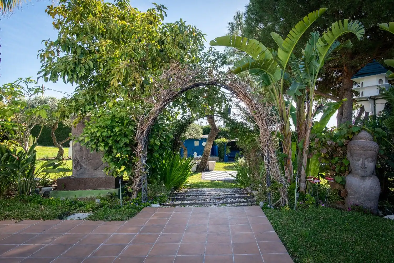 Beautiful garden entrance with lush greenery and decorative statues in Estepona.