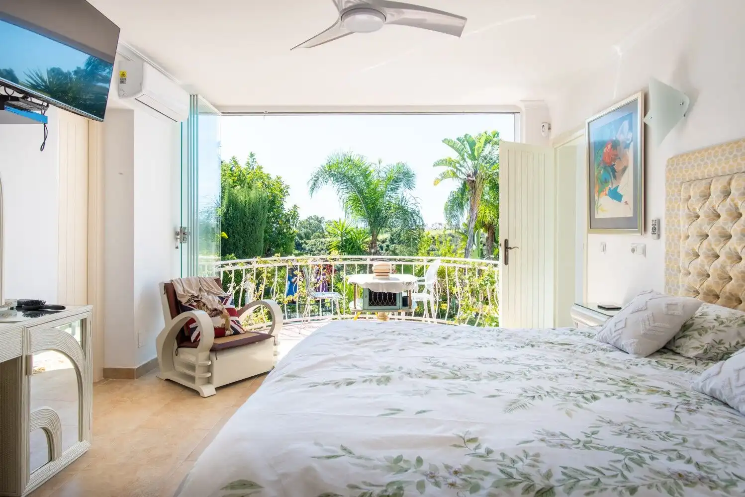 Spacious bedroom with balcony, tropical views, and bright decor in Los Llanos, Estepona.