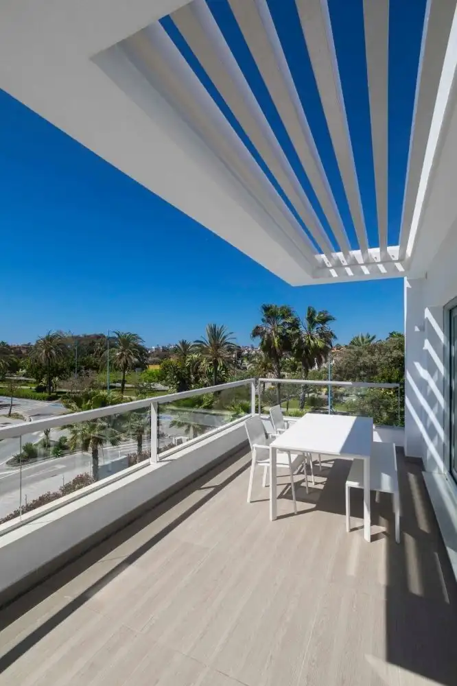 Spacious balcony of a contemporary penthouse overlooking the sea and lush greenery.