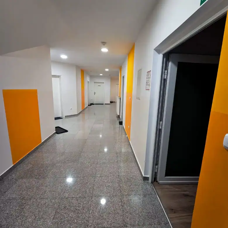 Bright commercial office hallway with yellow wall accents and elevator access.