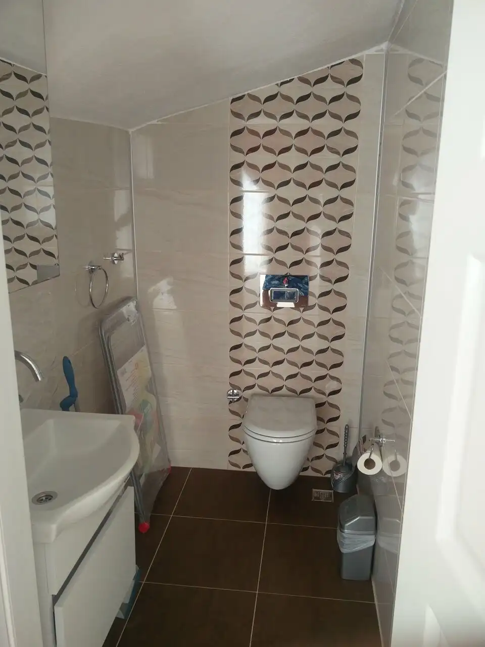 Bathroom with stylish tiles, toilet, and sink in a contemporary apartment.