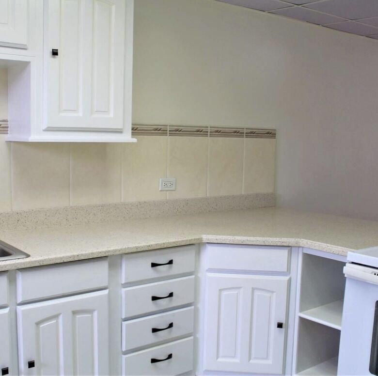 Modern kitchen with white cabinetry and beige countertops, ideal for comfortable living.