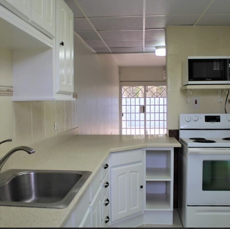 Modern kitchen with white cabinets and appliances in Maraval Trinidad.