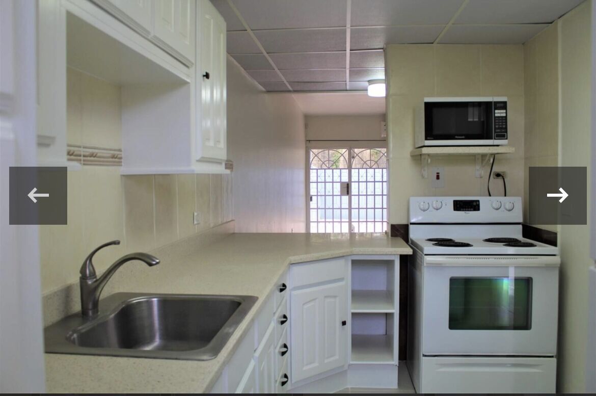 Modern kitchen with white cabinets and appliances in Maraval Trinidad.