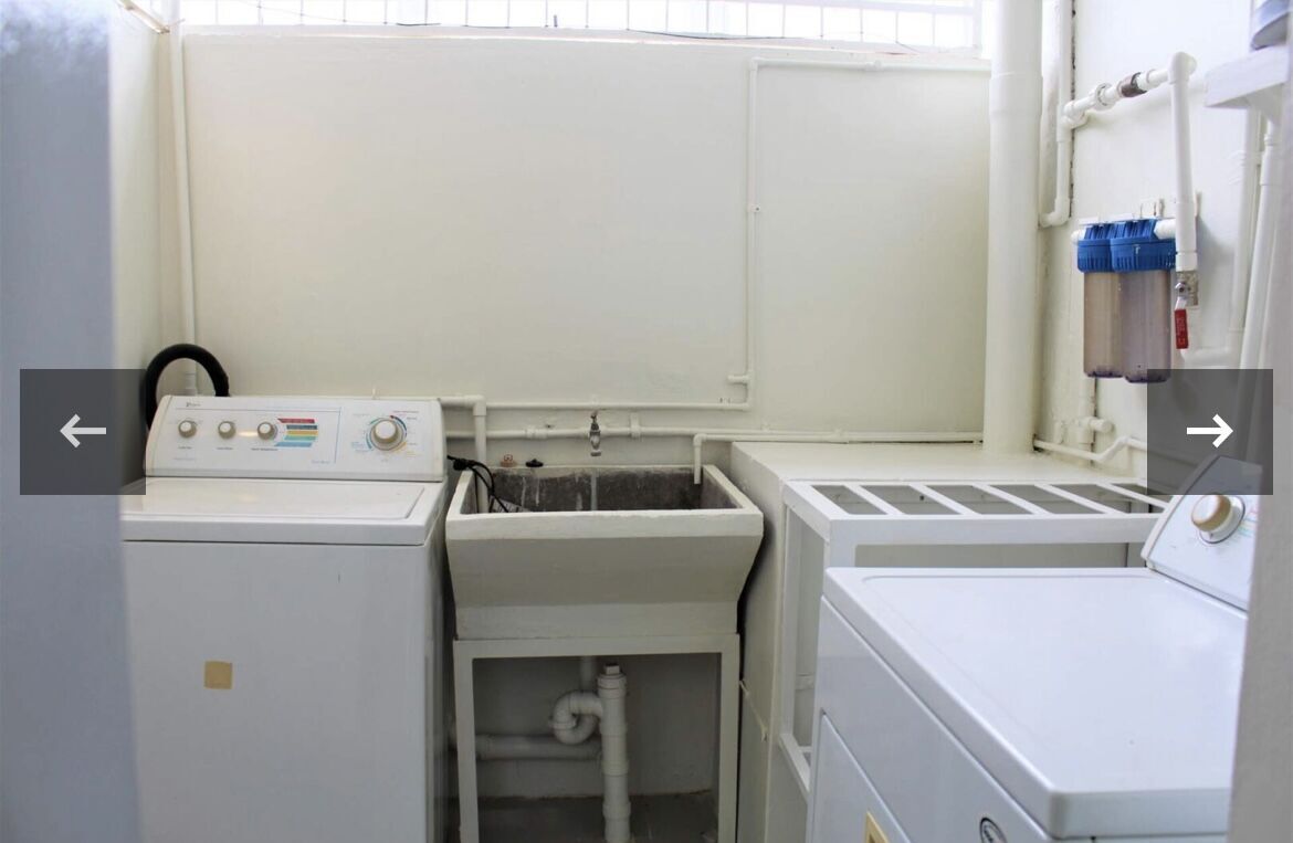 Efficient laundry area with washer, dryer, and utility sink in Trinidad townhouse.
