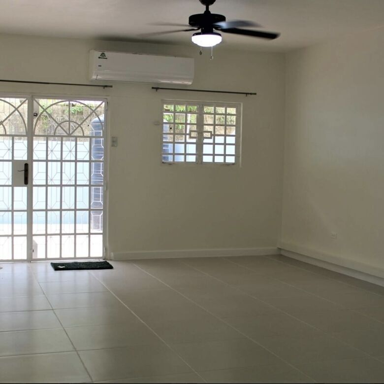 Spacious living area in a townhouse with large sliding glass doors, ceiling fan, and natural light i.