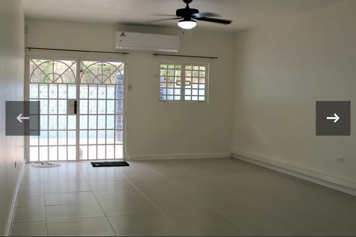 Spacious living area in a townhouse with large sliding glass doors, ceiling fan, and natural light i.