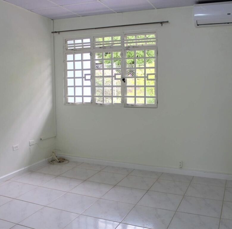 Spacious room with white walls, tiled floor, and natural light from the window.