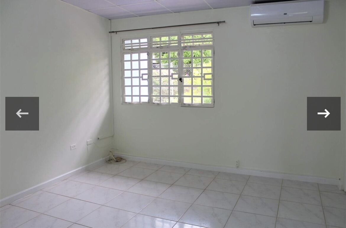Spacious room with white walls, tiled floor, and natural light from the window.