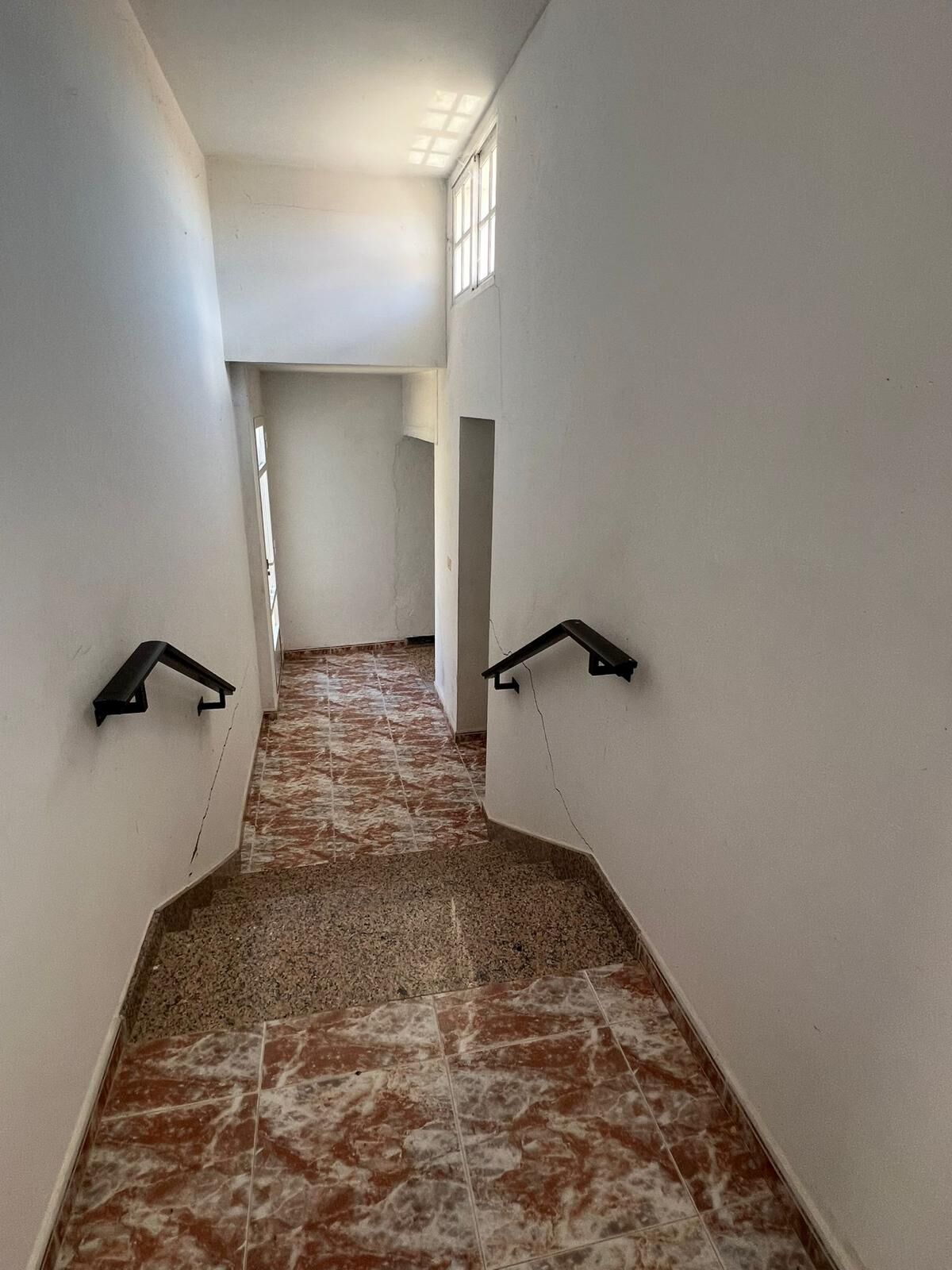 Interior staircase with black handrails in a bright, airy house in Taboada, Galicia.