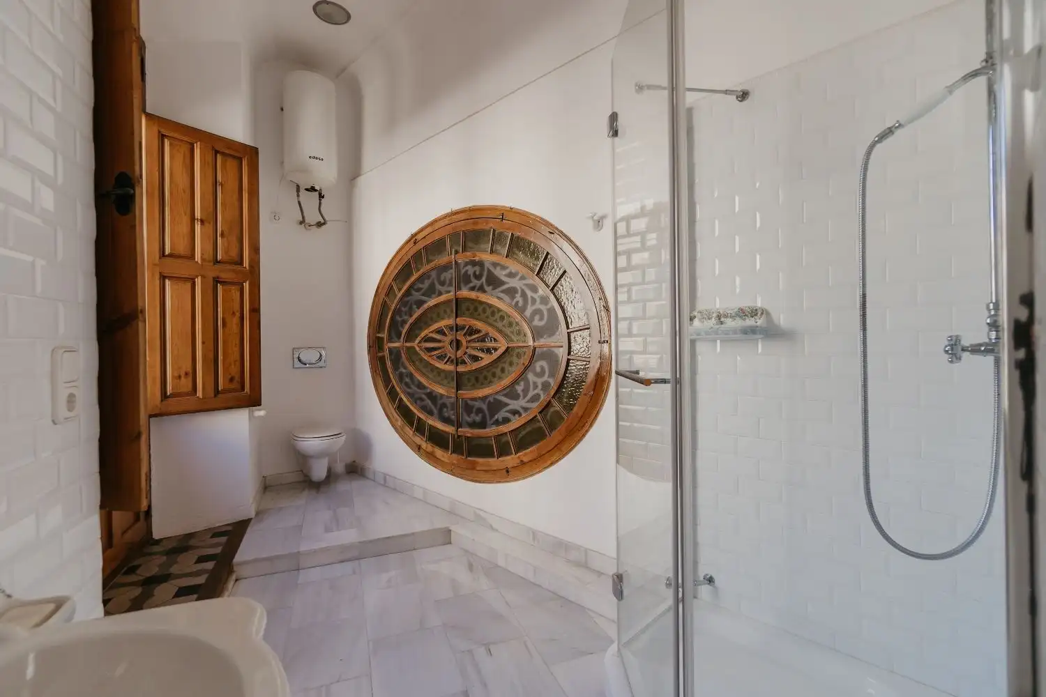 Bright bathroom in Malaga penthouse with modern shower and unique circular window.