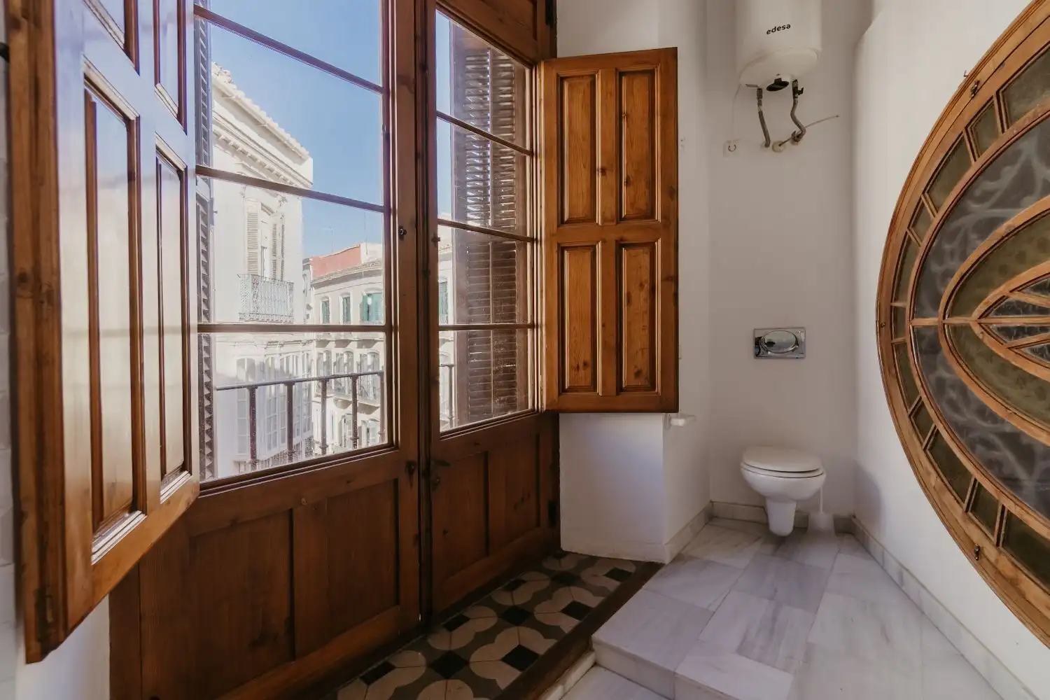 Bright Malaga penthouse bathroom with large windows and cityscape view.
