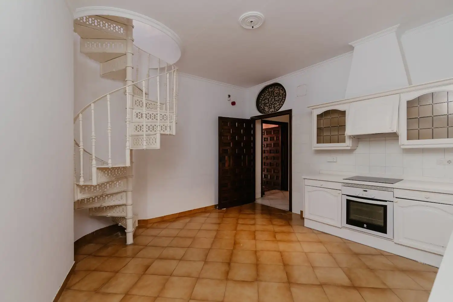 Penthouse living area in Malaga city center with modern kitchen and spiral staircase.