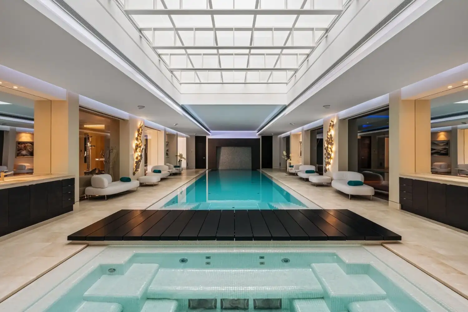 Indoor swimming pool with elegant lighting and contemporary decor in a luxury mansion.