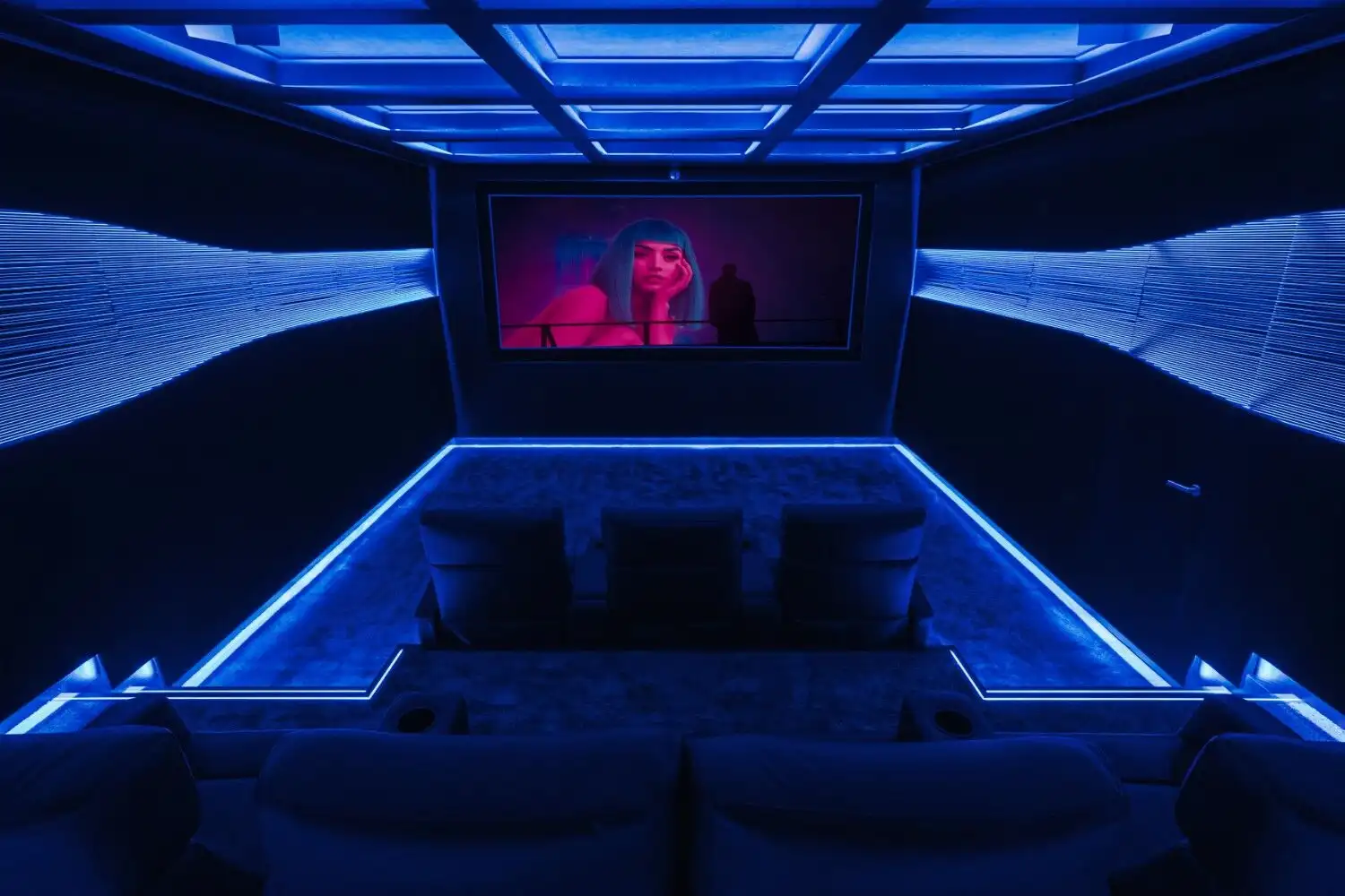 Luxury home theater featuring blue LED lighting and a large screen for an immersive viewing experien.