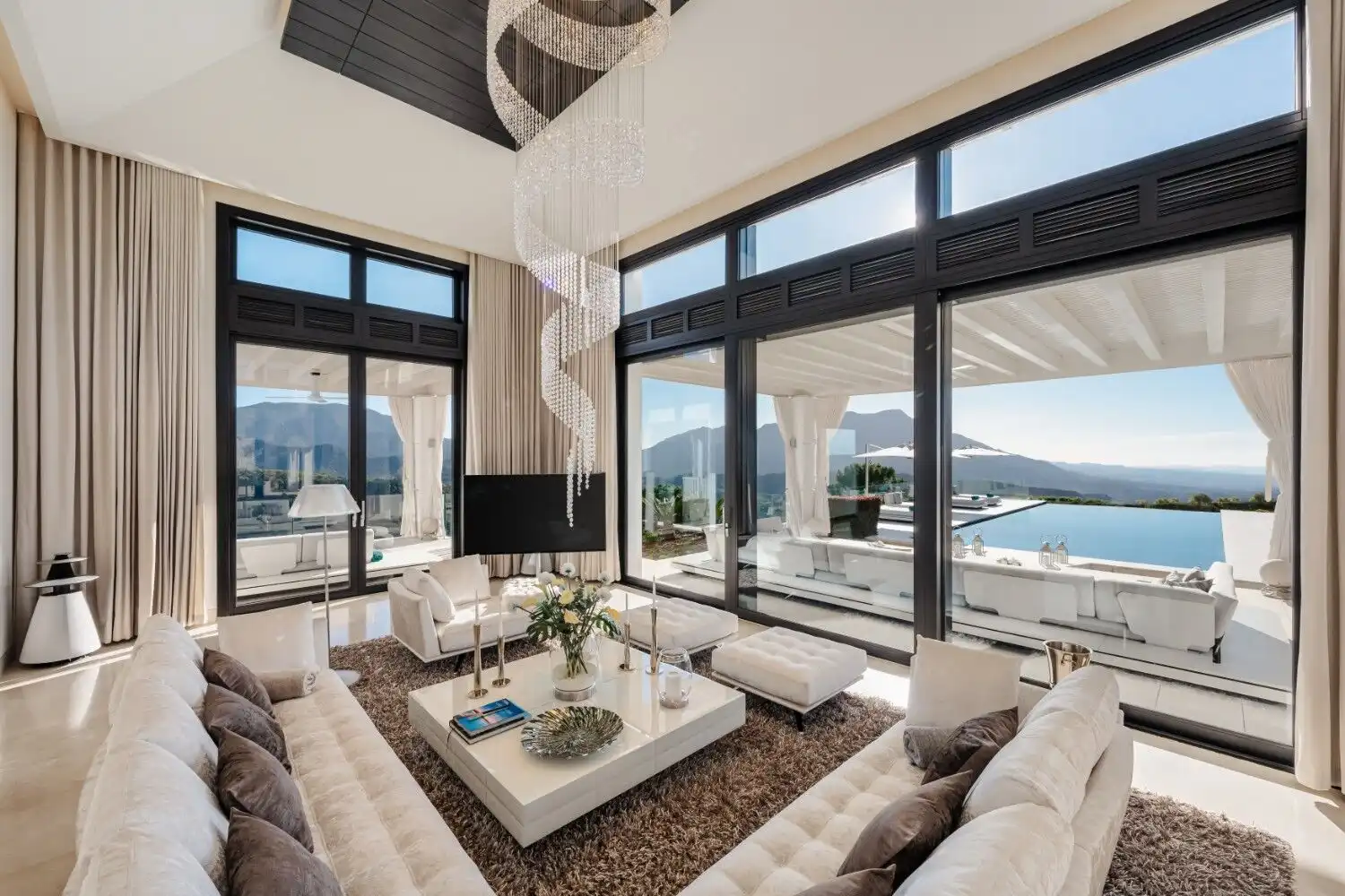 Elegant living room featuring floor-to-ceiling windows overlooking scenic landscapes and the sea. Pe.