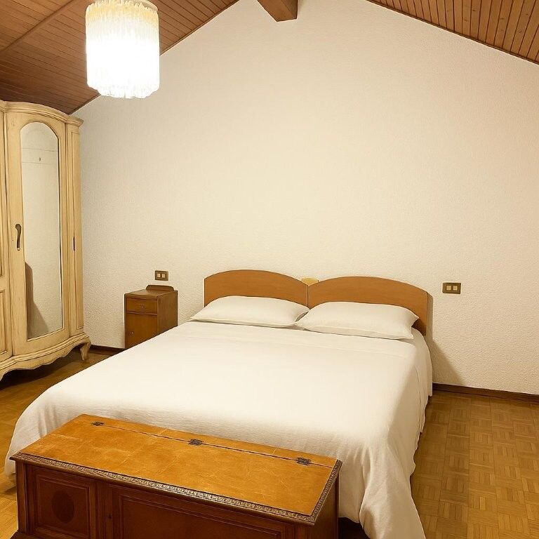 Comfortable bedroom with a large bed and wooden furniture in a charming Italian villa.