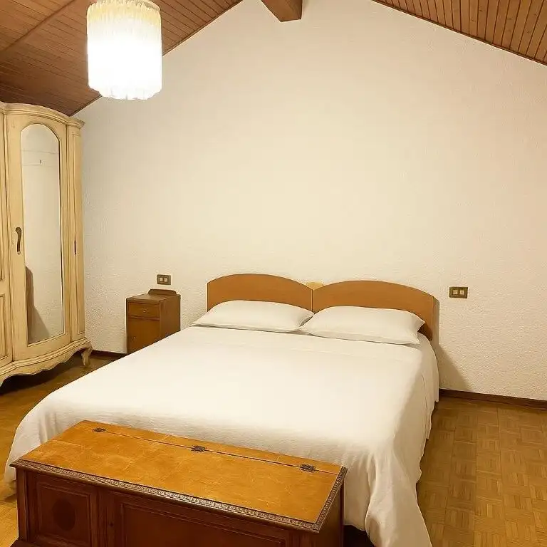 Comfortable bedroom with a large bed and wooden furniture in a charming Italian villa.
