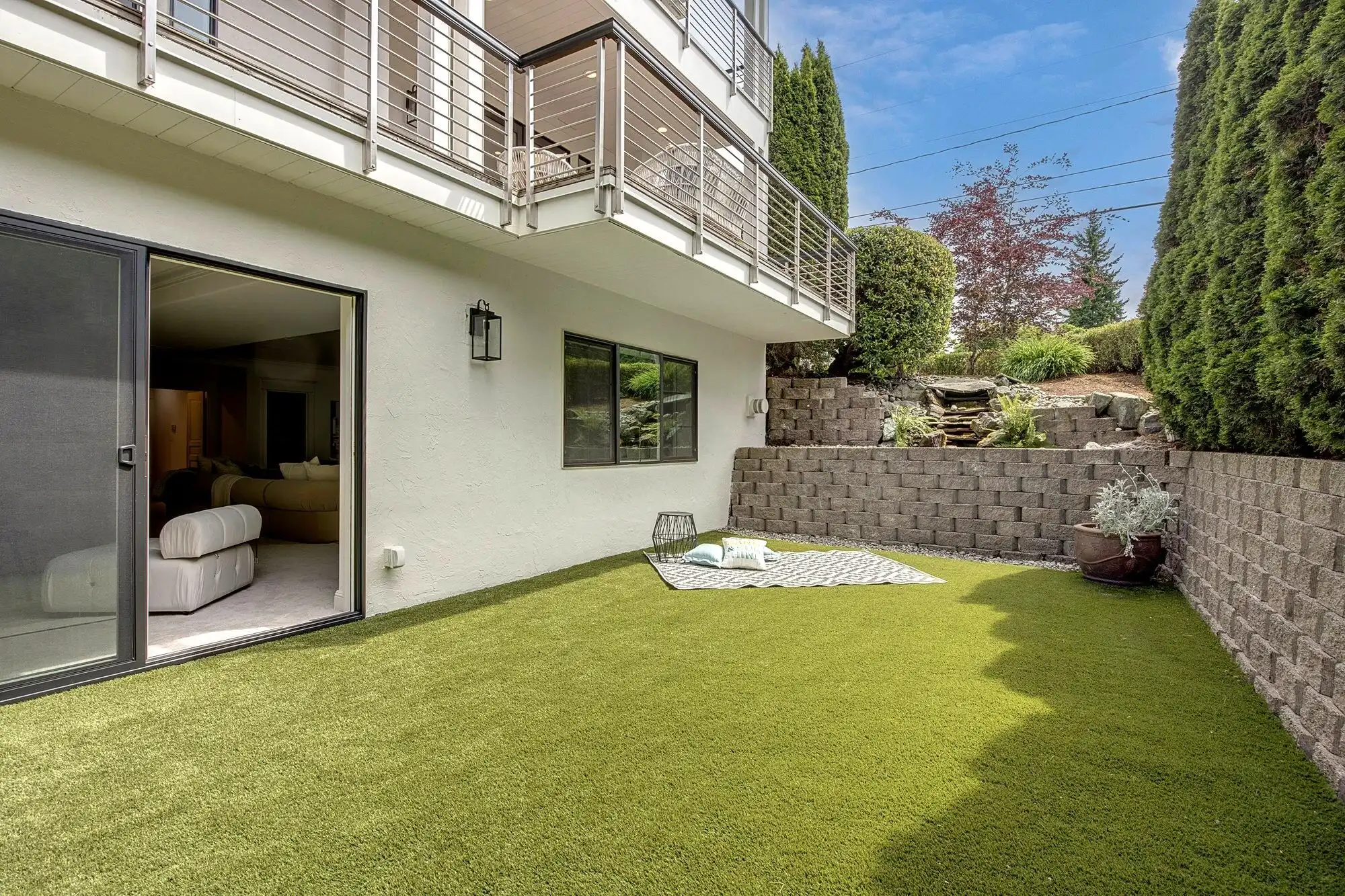Beautiful backyard of a luxury lakefront home with lush green lawn and modern balcony.