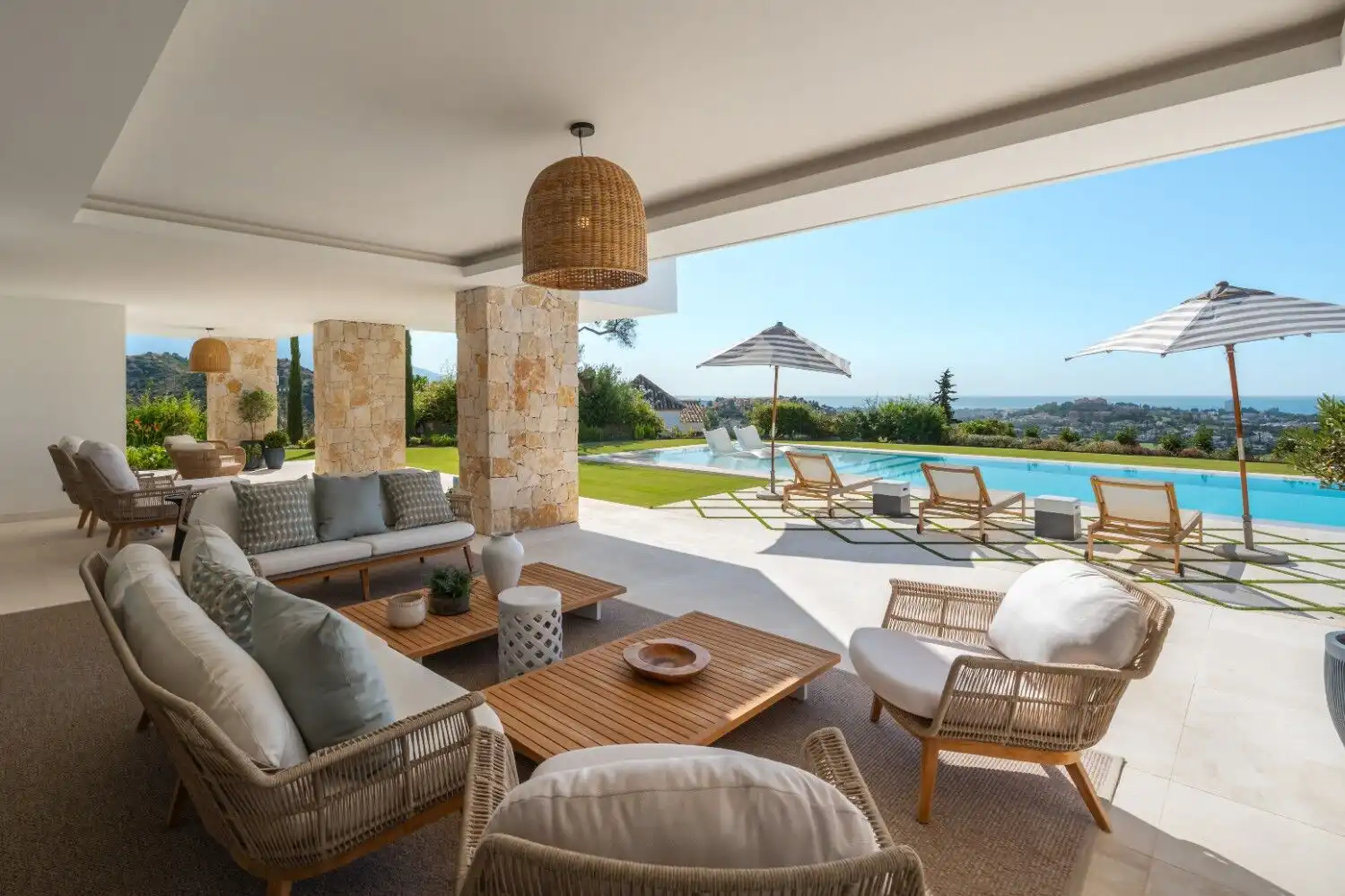 Luxury villa terrace overlooking pool and ocean scenery.