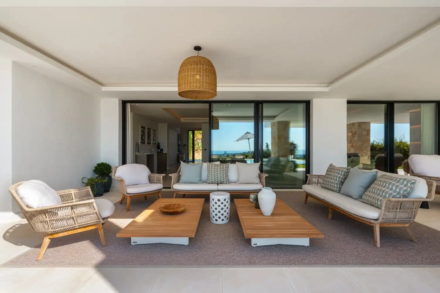Elegant outdoor lounge with ocean backdrop and modern furniture.
