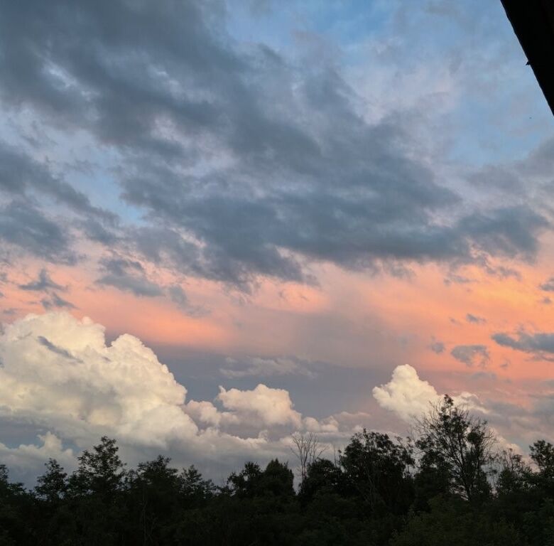 Beautiful sunset view over Mezzana Mortigliengo with a partly cloudy sky and lush greenery.