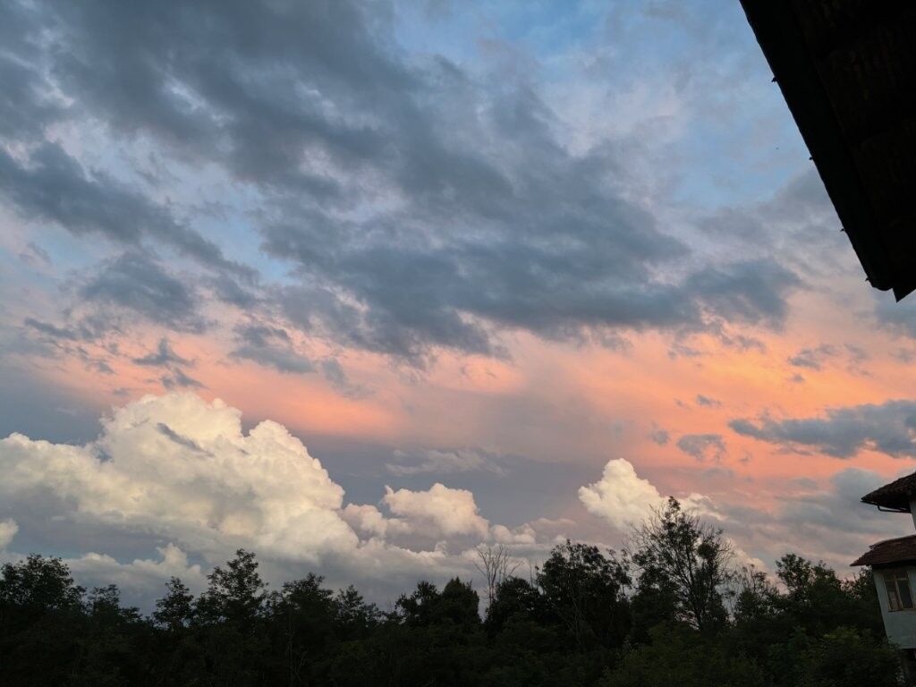 Charming Villa in Mezzana Mortigliengo Italy Beautiful sunset view over Mezzana Mortigliengo with a partly cloudy sky and lush greenery.
