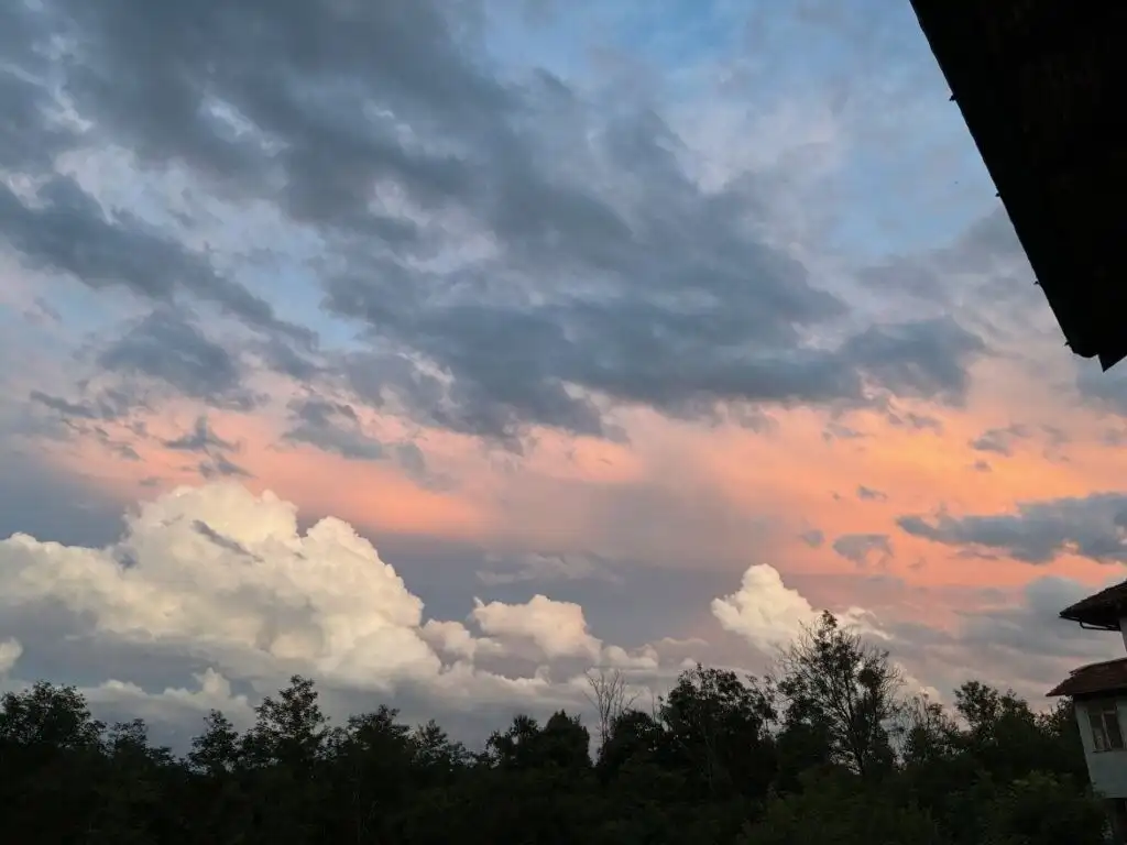 Beautiful sunset view over Mezzana Mortigliengo with a partly cloudy sky and lush greenery.