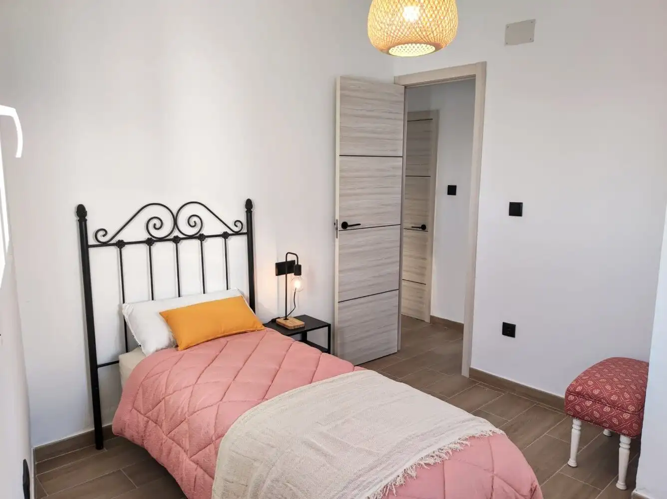 Charming bedroom with black wrought iron bed, pink bedding, and modern decor in Torresoto.