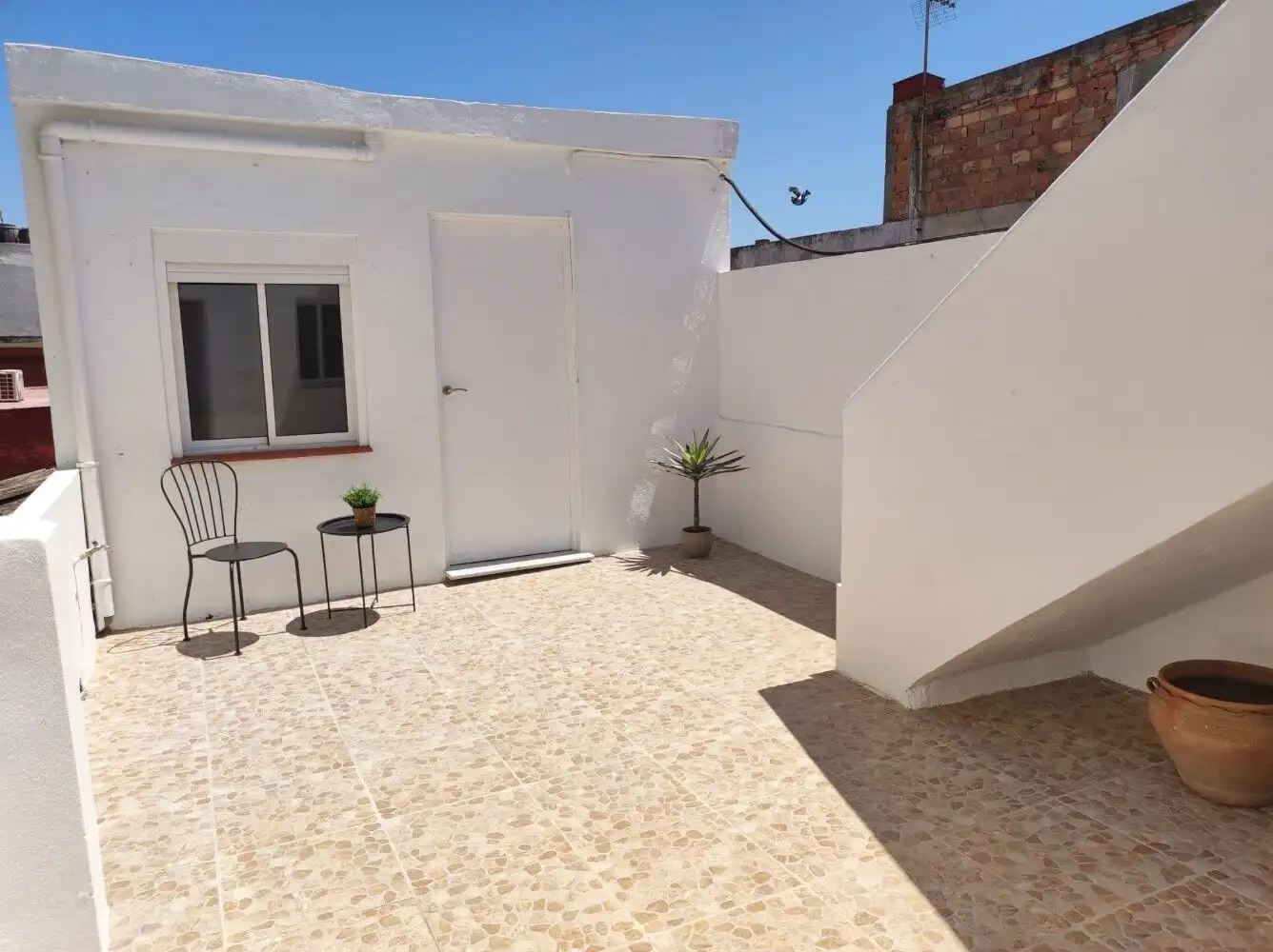 Small outdoor patio of a Torresoto independent casita with seating and potted plants.