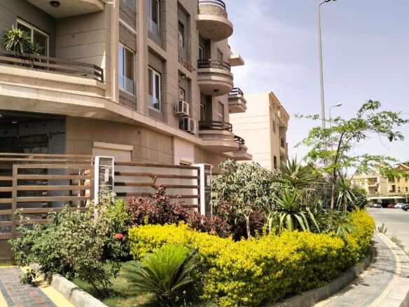 Modern apartment building with landscaped garden in New Cairo.
