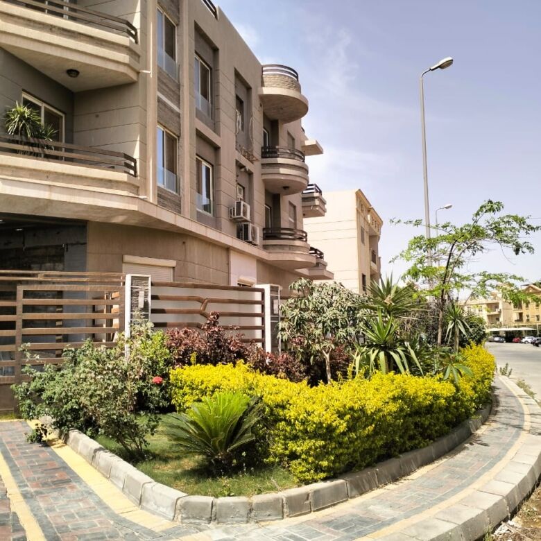 Modern apartment building with landscaped garden in New Cairo.