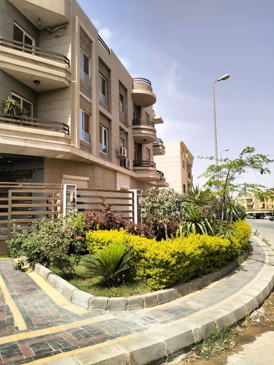 Modern apartment building with landscaped garden in New Cairo.