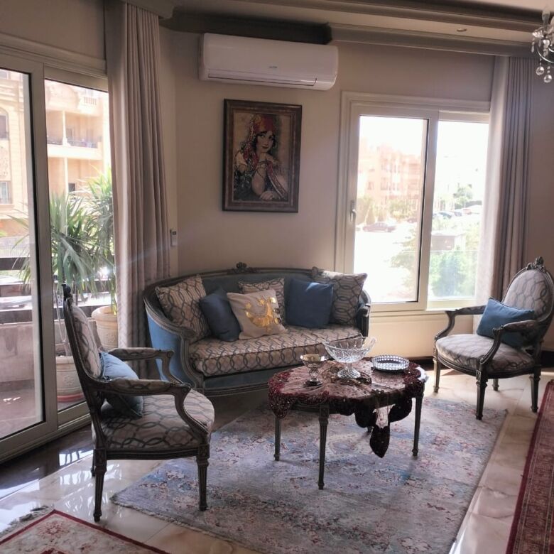 Elegant living room with classic furniture and large windows in New Cairo apartment.