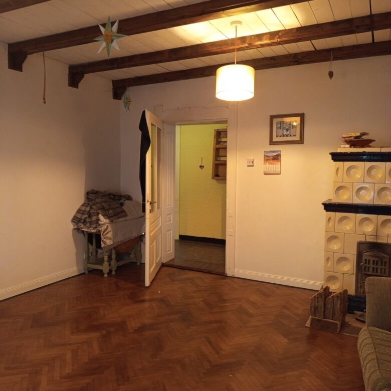 Cozy living room with wooden beams and warm lighting in Vulcan Brasov home for sale.