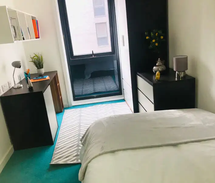 Bright student apartment bedroom with large window and balcony access in Sheffield.