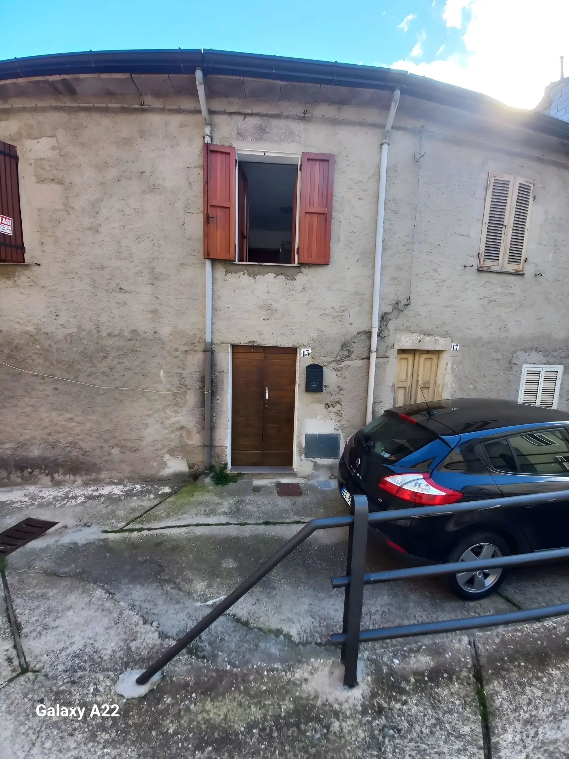 Story house in historic Pattada, Sardinia, with wooden shutters and parking space.