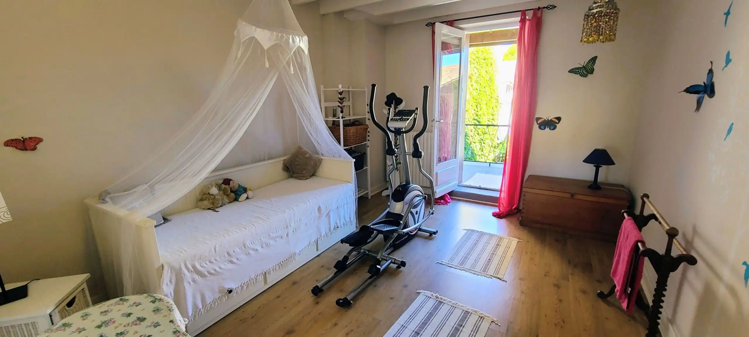 Bright bedroom with exercise equipment and butterfly wall decor in a charming home.