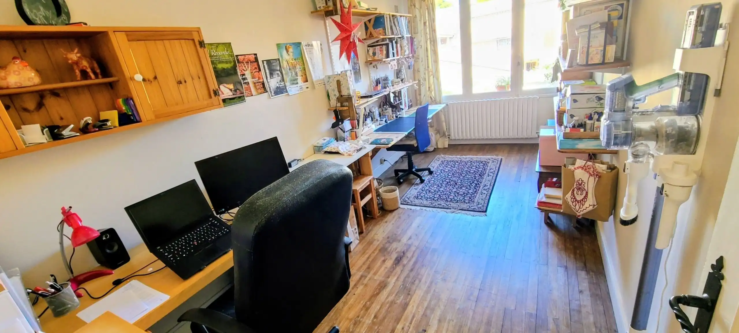 Bright home office with desks, computers, and shelves in a cozy, well-lit room.