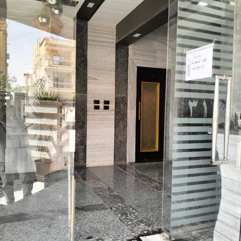 Modern entrance of a luxury 3-bedroom apartment in New Cairo with glass doors and elegant interior d.