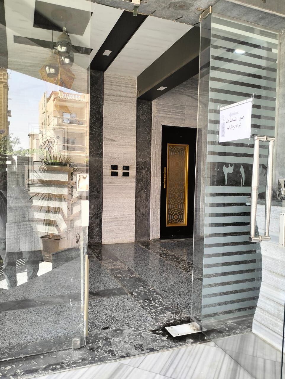 Modern entrance of a luxury 3-bedroom apartment in New Cairo with glass doors and elegant interior d.