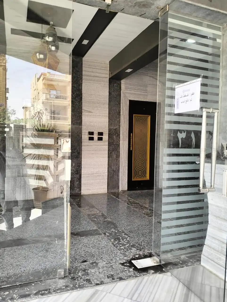 Modern entrance of a luxury 3-bedroom apartment in New Cairo with glass doors and elegant interior d.