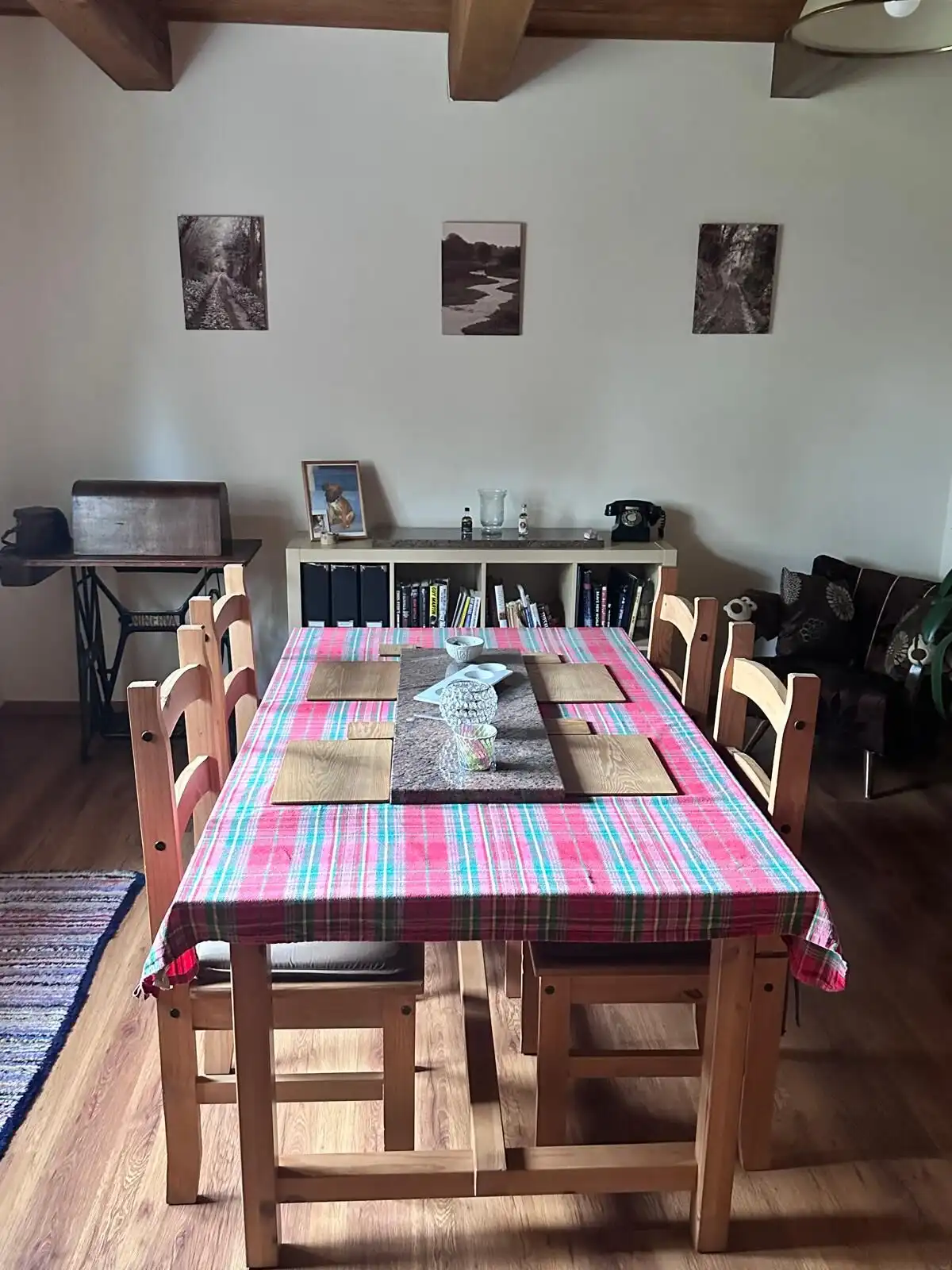 Spacious dining area featuring a wooden table with a colorful tablecloth, surrounded by matching cha.
