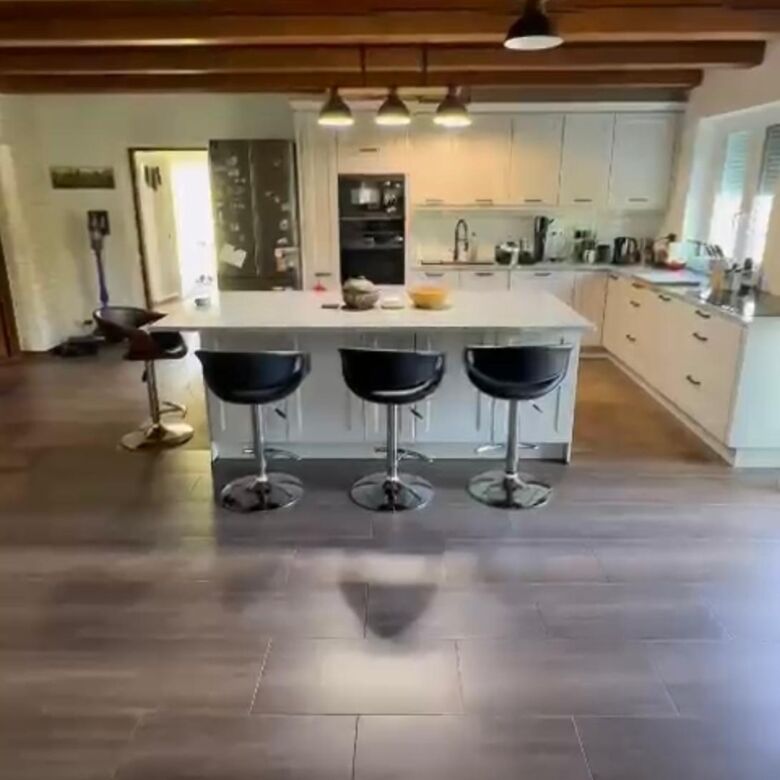 Spacious modern kitchen with island, stylish bar stools, and wooden ceiling beams in a beautiful rur.