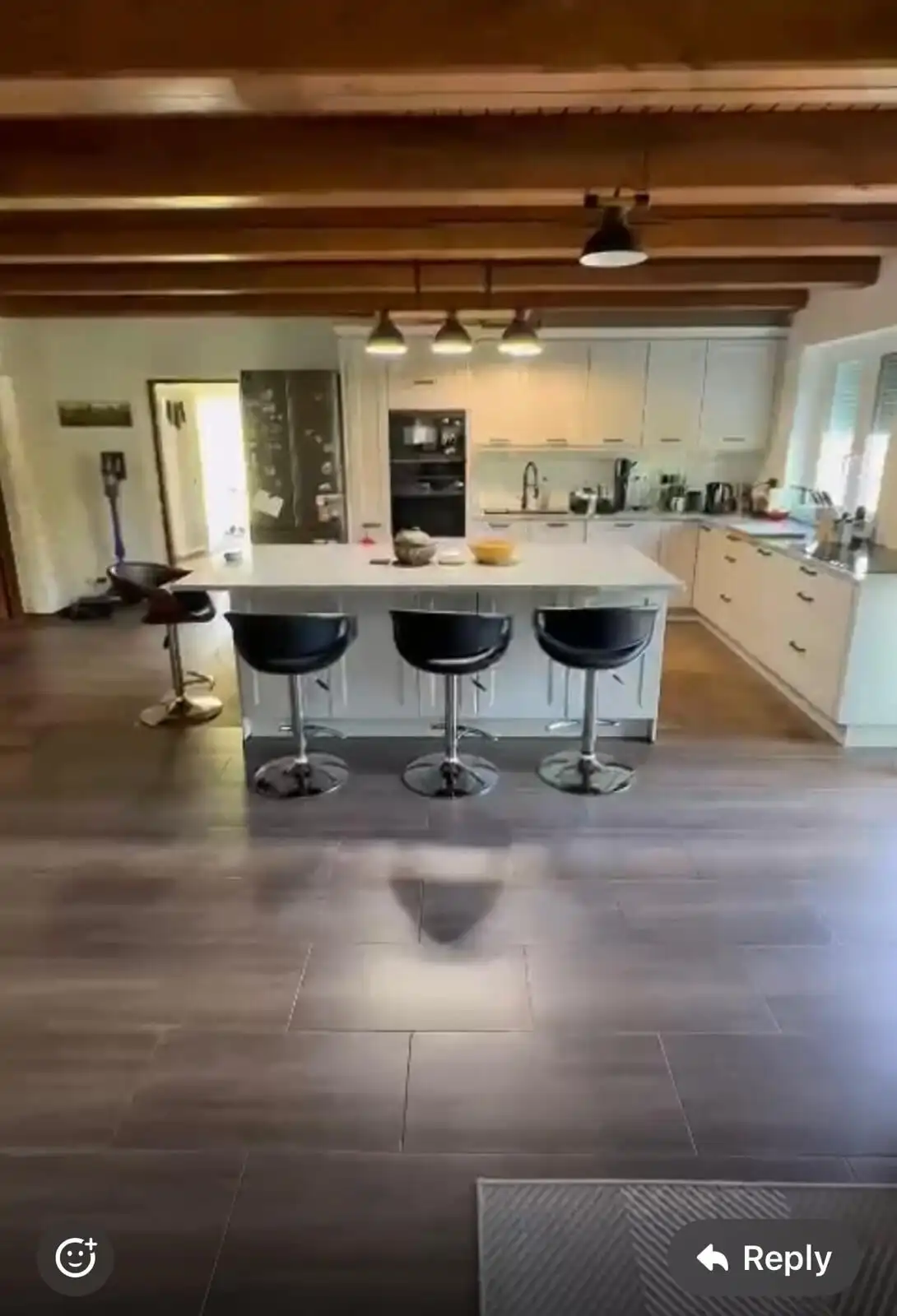 Spacious modern kitchen with island, stylish bar stools, and wooden ceiling beams in a beautiful rur.
