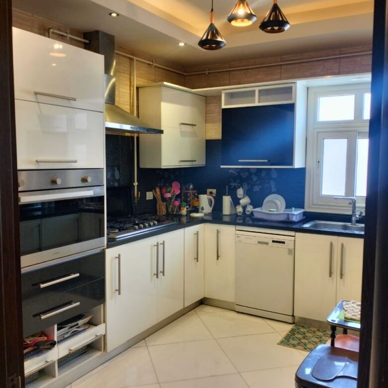 Modern kitchen with sleek white cabinets and black countertops in New Cairo.